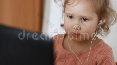 一个戴着耳机的小可爱女孩看着屏幕监视器<strong>电脑</strong>.. 看<strong>电视</strong>、录像、<strong>卡通</strong>或玩游戏的滑稽儿童